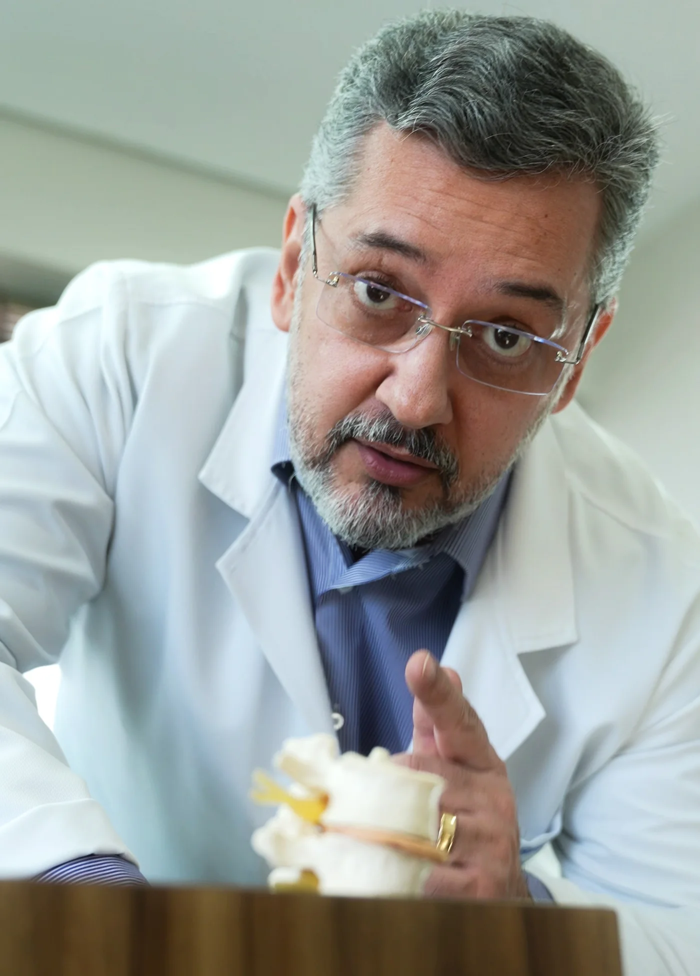 Dr. Vladmir Resende, neurocirurgião de coluna, explicando a anatomia vertebral com um modelo de vértebra